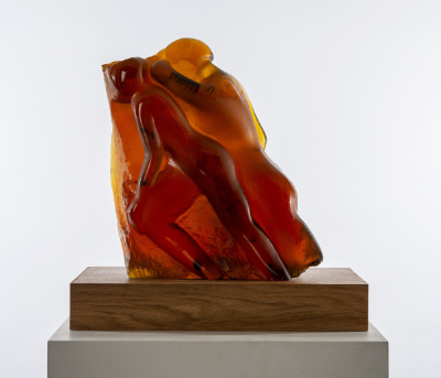 A dark orange cast glass sculpture depicting two human figures.