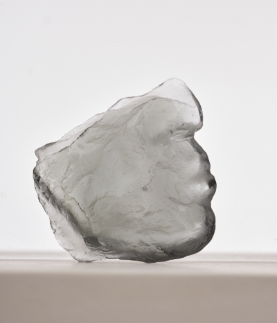 Cast glass sculpture showing part of a human face.