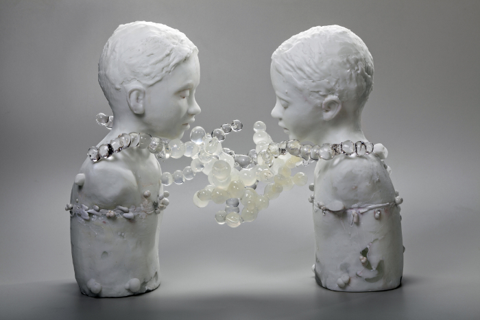 Thaw sculpture featuring two children made from kiln-cast and hot moulded glass 