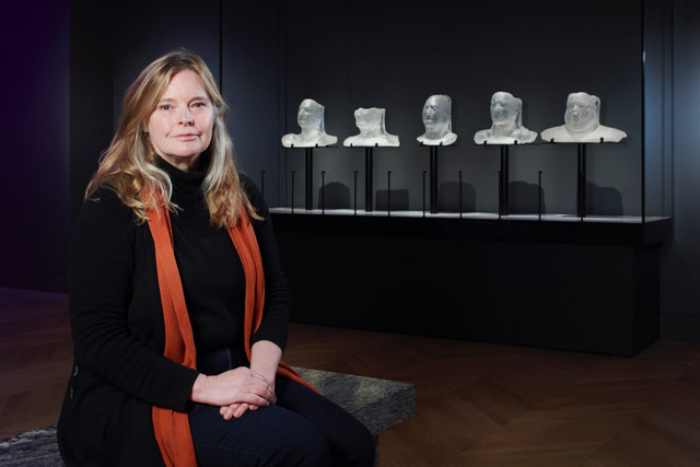 Katharine Dowson sitting in front of glass head installation she made at the Science Museum.