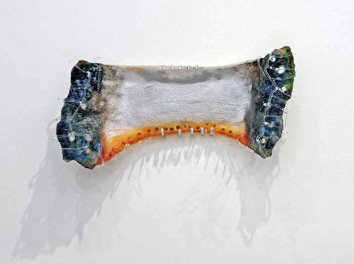 A piece of glass art in blue, orange and white tones made from flameworked and pate de verre techniques