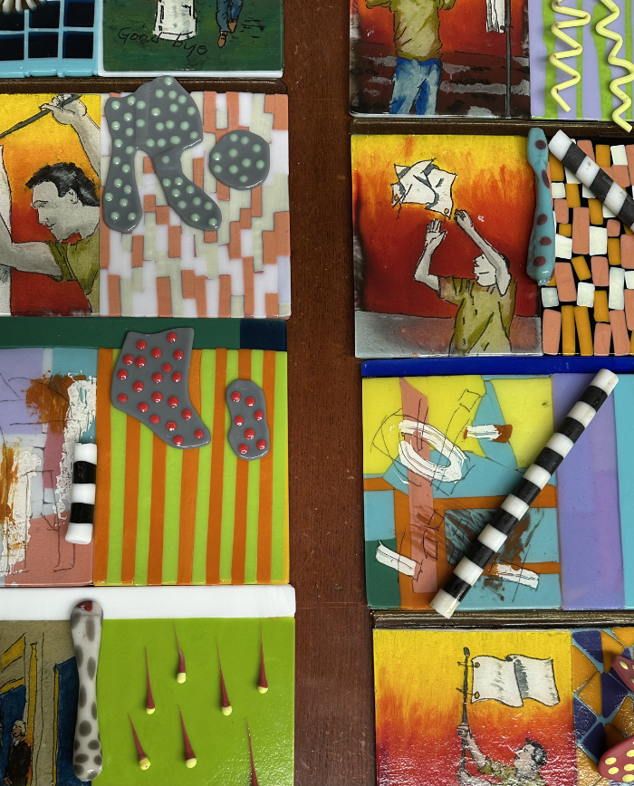 A series of brightly colourful reverse-painted glass tiles with fused glass additions laid on top ready for moulding into vessels.