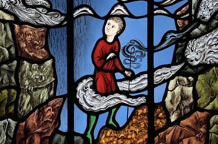 A painted stained glass panel featuring a figure in clouds and landscape by Jonathan Cooke.