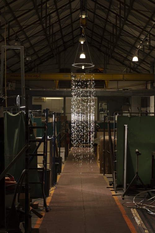 View of glass installation made from 1000 flame worked glass leaves hanging down in strings from a circular frame.
