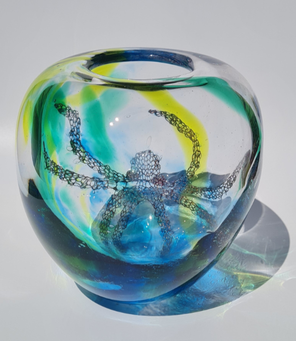 Glass rounded vessel featuring yellow, blue and green glass and an octopus.