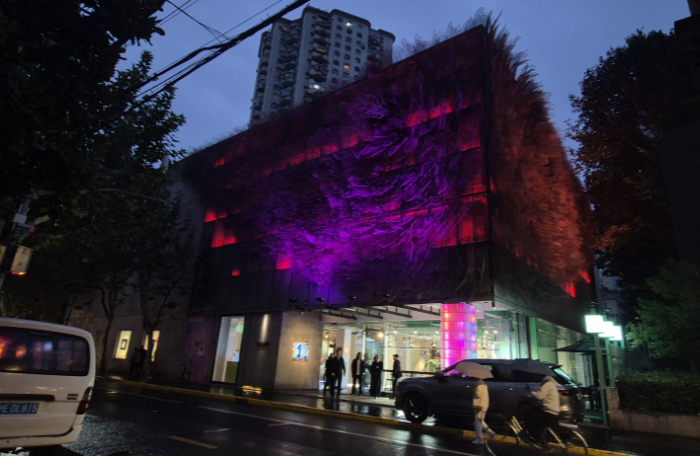 Outside view of Liuli Museum of Glass at night showing pink and purple lights highlighting a pointy textured wall.