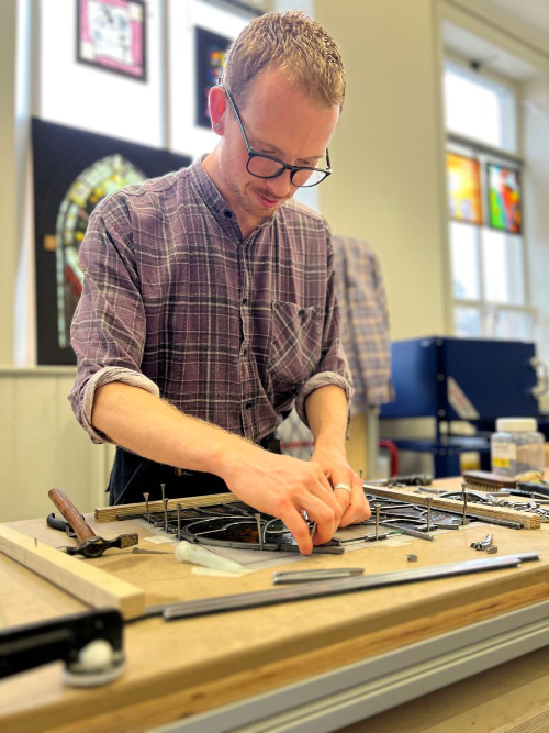 Toby Britton-Watts working on a stained glass window in the studio.