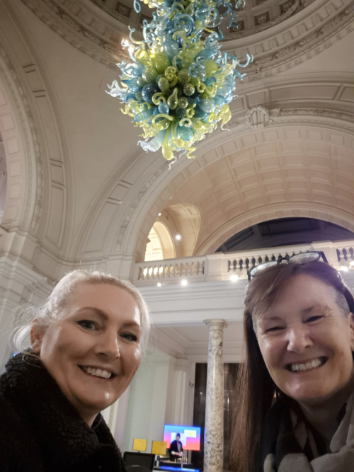 Sarah Brown and Helen Slater Stokes with glass chandelier in background by Dale Chihuly.