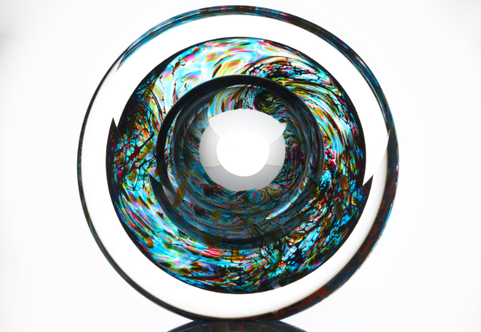 A piece of round blown glass featuring many different colours swirling around by Tim Rawlinson.