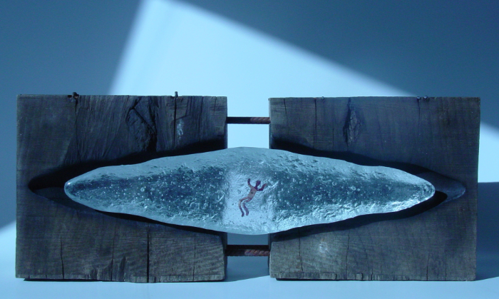 An old glass mould supports clear sand-cast glass featuring a swimming figure in the centre made from copper. The pure human figure swims uninhibited in the glass 'sea'. 