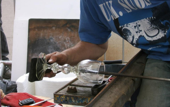 Glassblower Ian Hankey making a glass goblet using an ancient Venetian glass recipe. Image shows him shaping the bowl of the goblet.