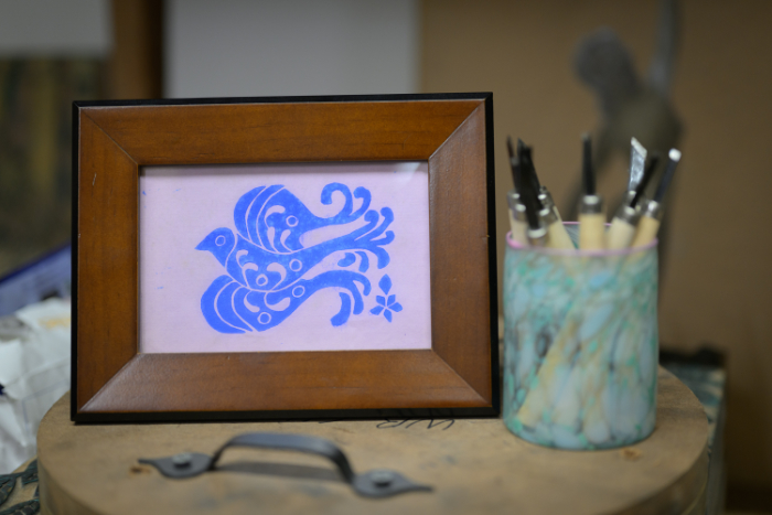 A framed woodblock print of a bird next to Trish's Japanese carving tools.
