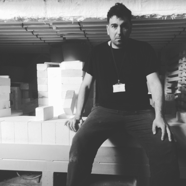 Antonis Koutouzis sitting in the casting studio with moulds in the background.