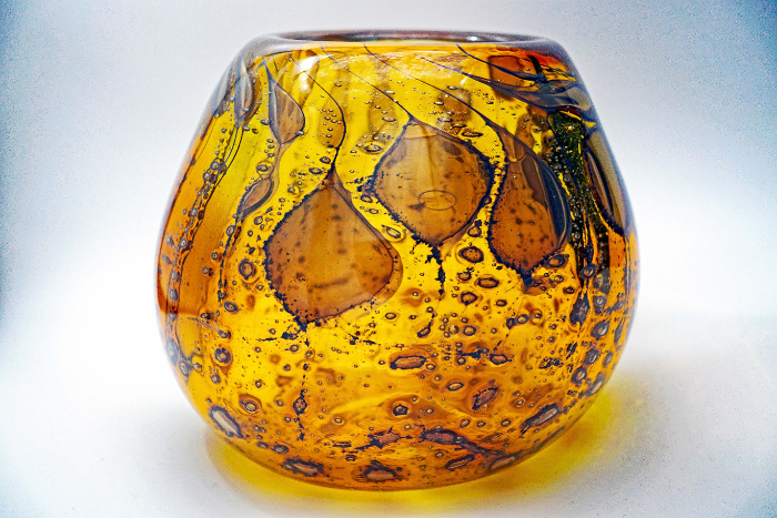 A blown glass amber coloured bowl infused with darker amber organic shapes from honey infusions.