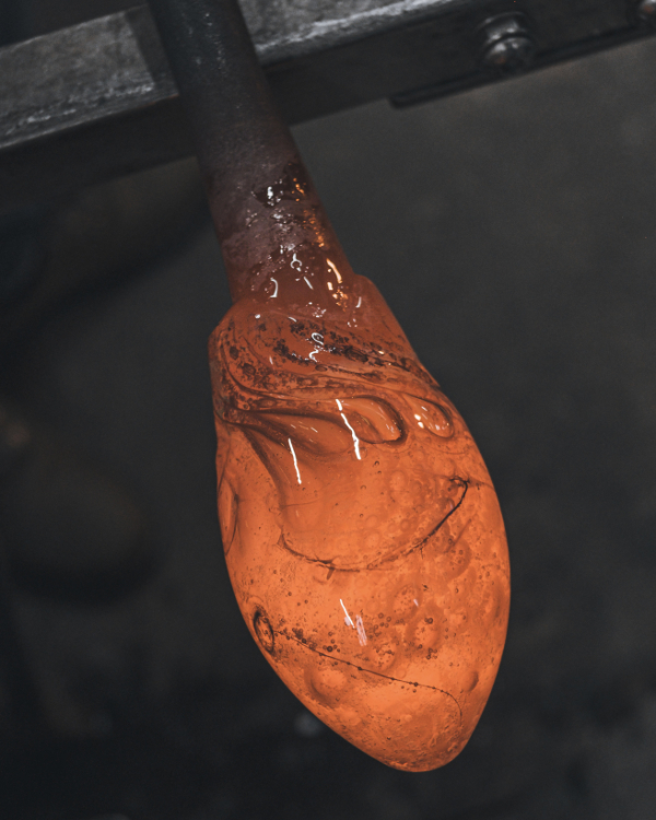 Molton glass glowing orange on the blowing pole showing darker marks from infusion with honey.