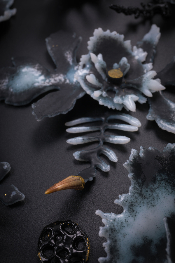 Glass sculptures inspired by nature in shapes of flowers and leaves in dark grey and white tones.
