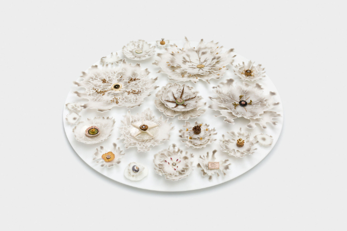White glass circular base supporting numerous highly delicate and detailed naturalistic and fantasy shapes inspired by the natural world and made from pate de verre glass and other glass techniques.