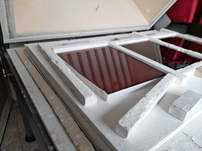 Three rectangular, newly cast glass slabs sitting in an open flatbed kiln ready for carving.