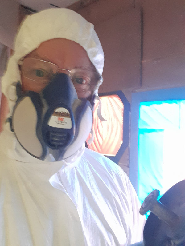 Glass carving expert Jonathan Soper in protective clothing including a full overall with hood and respirator.