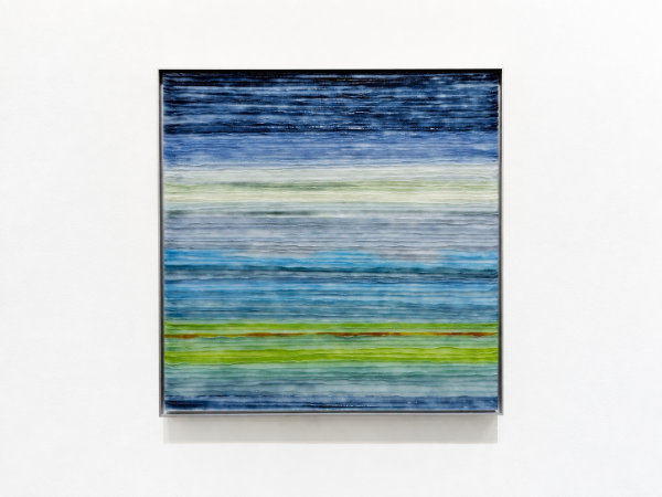 Square wall art of textured, kiln-formed glass in horizontal tones of green and blues giving the impression of a landscape or seascape with sky.